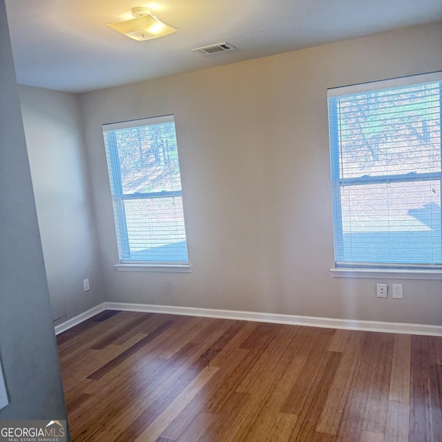 spare room featuring wood finished floors, baseboards, and visible vents