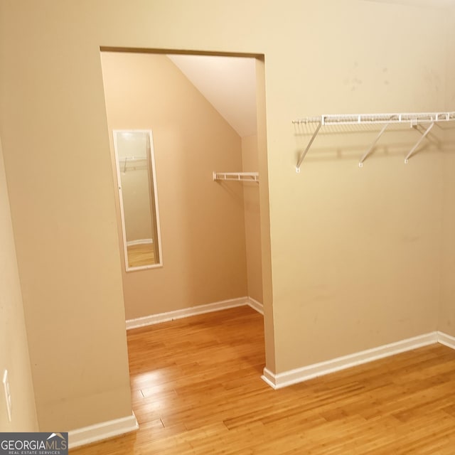 spacious closet featuring light wood-type flooring and lofted ceiling