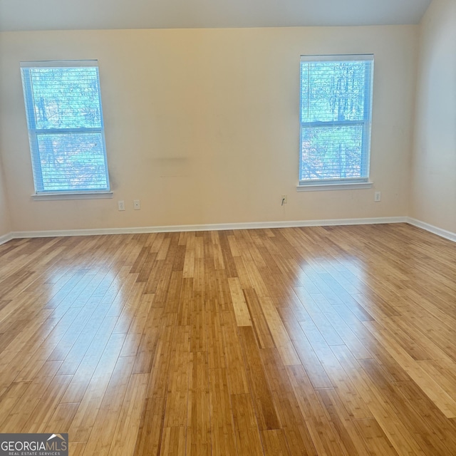 empty room featuring light wood-type flooring, a healthy amount of sunlight, and baseboards