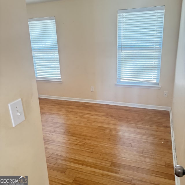 spare room with wood finished floors, baseboards, and a wealth of natural light