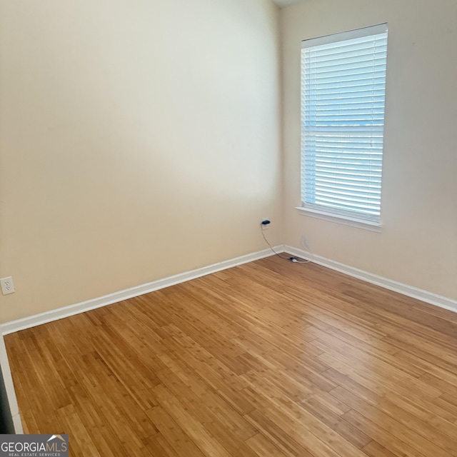 spare room featuring baseboards and light wood finished floors