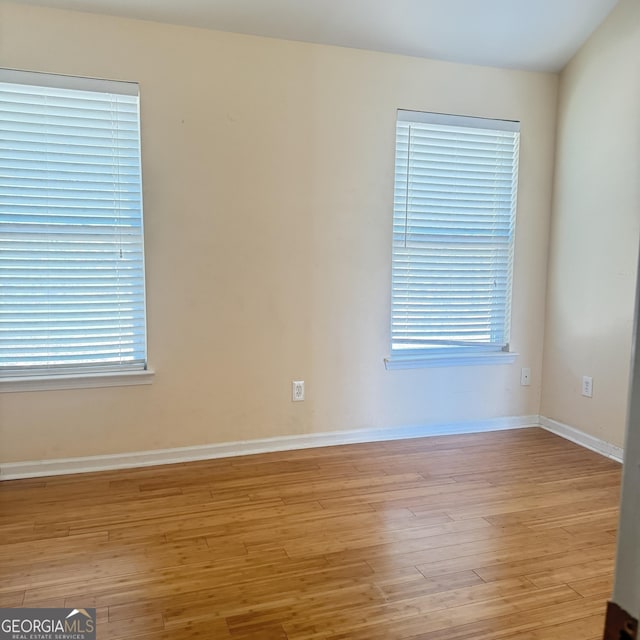 empty room featuring light wood-type flooring, a healthy amount of sunlight, and baseboards