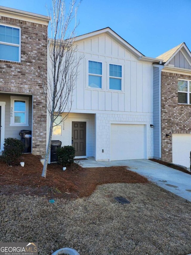 townhome / multi-family property featuring driveway, brick siding, board and batten siding, and an attached garage