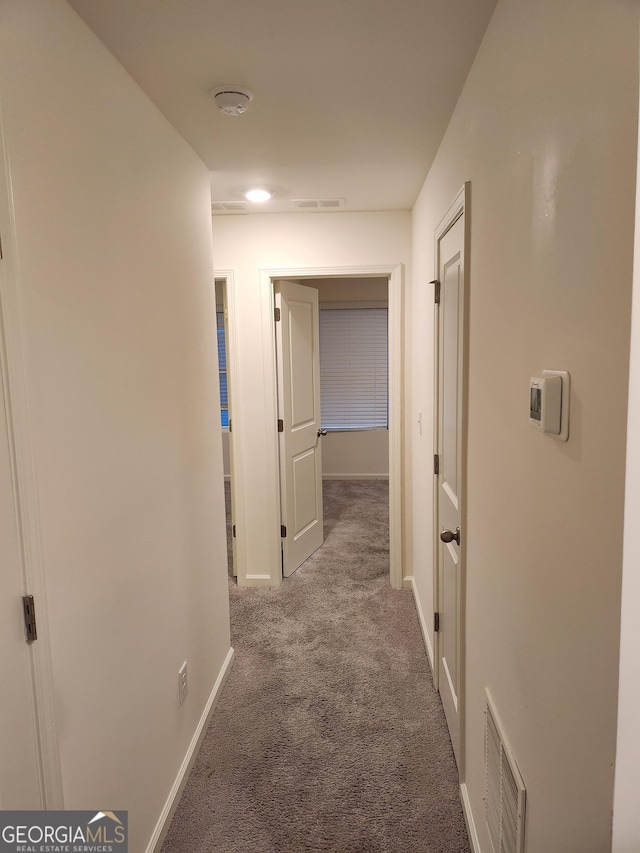 hall with carpet, visible vents, and baseboards