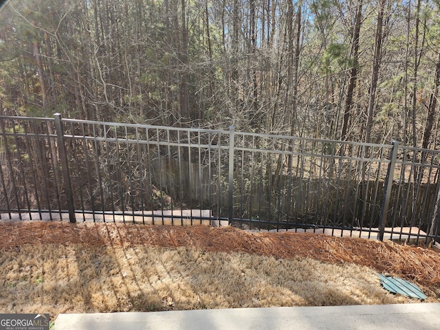 view of yard with a forest view and fence