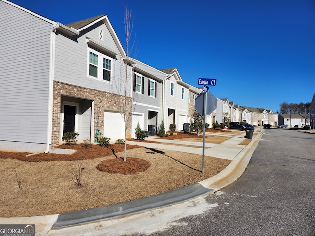 view of road featuring traffic signs, sidewalks, a residential view, and curbs