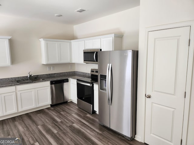 kitchen featuring stainless steel appliances, dark stone counters, a sink, white cabinetry, and dark wood-style floors