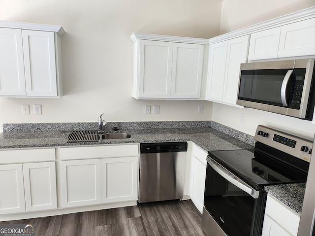 kitchen with appliances with stainless steel finishes, white cabinets, a sink, and dark wood-type flooring