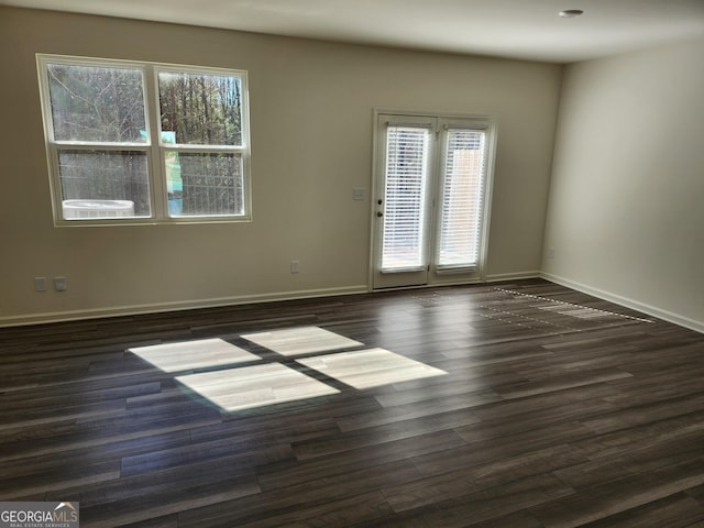 empty room with baseboards, a wealth of natural light, and wood finished floors