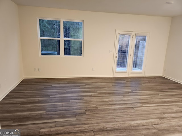 empty room with a healthy amount of sunlight, baseboards, and wood finished floors