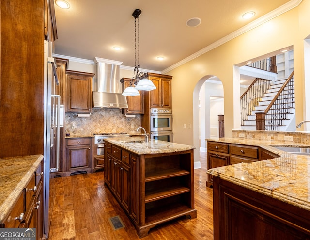 kitchen with wall chimney range hood, stainless steel double oven, a sink, and visible vents