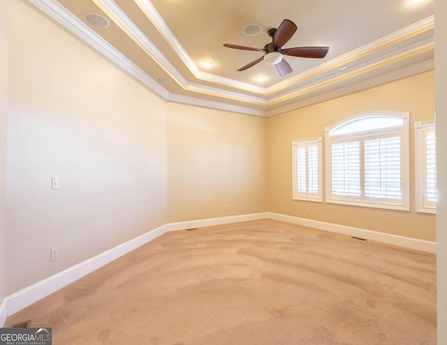 spare room featuring baseboards, a raised ceiling, a ceiling fan, carpet, and crown molding