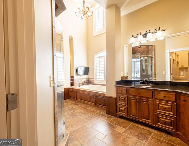 bathroom featuring a garden tub, a notable chandelier, stone tile floors, vanity, and a stall shower