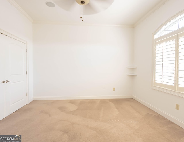 carpeted spare room with a ceiling fan, crown molding, and baseboards