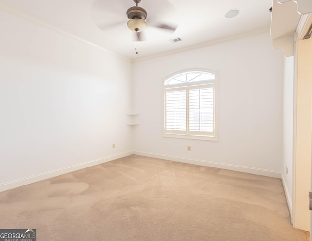 unfurnished room with crown molding, light colored carpet, visible vents, a ceiling fan, and baseboards