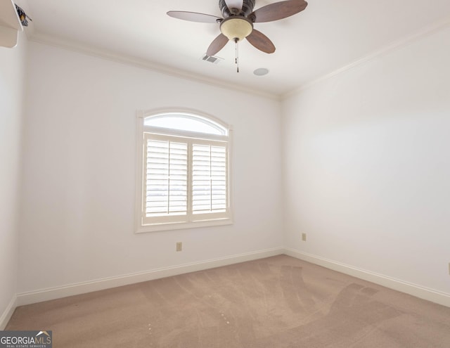 empty room with ceiling fan, light colored carpet, visible vents, baseboards, and crown molding