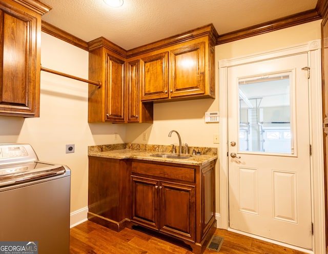 kitchen featuring brown cabinetry, washer / clothes dryer, a sink, and dark wood-style flooring