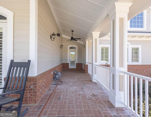 view of exterior entry with ceiling fan and brick siding