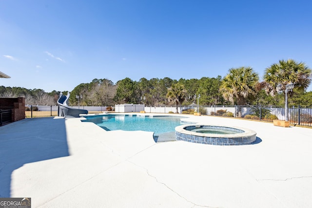 view of swimming pool featuring a water slide, fence, and a pool with connected hot tub