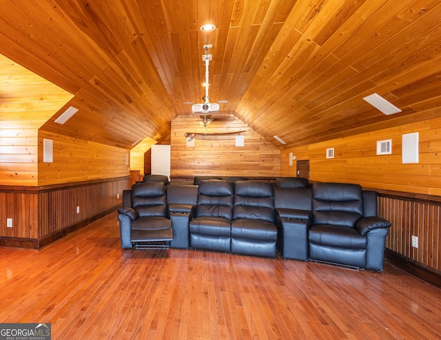 cinema room featuring vaulted ceiling, wood walls, wood finished floors, and wood ceiling