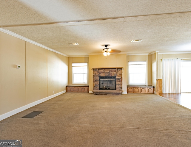 unfurnished living room with a stone fireplace, visible vents, and crown molding