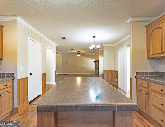 kitchen with dark countertops, visible vents, a kitchen island, and wood finished floors