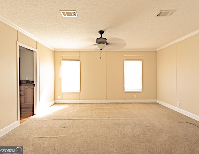 carpeted empty room with plenty of natural light, visible vents, and crown molding