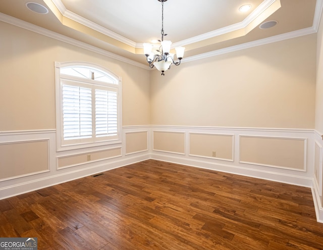 unfurnished room with a notable chandelier, dark wood-type flooring, visible vents, ornamental molding, and a raised ceiling