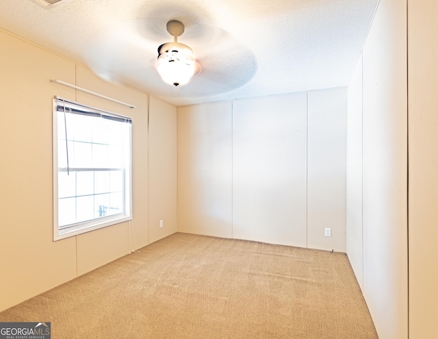 spare room with a textured ceiling and light colored carpet