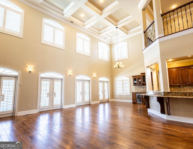 unfurnished living room with dark wood-style floors, french doors, an inviting chandelier, ornamental molding, and baseboards