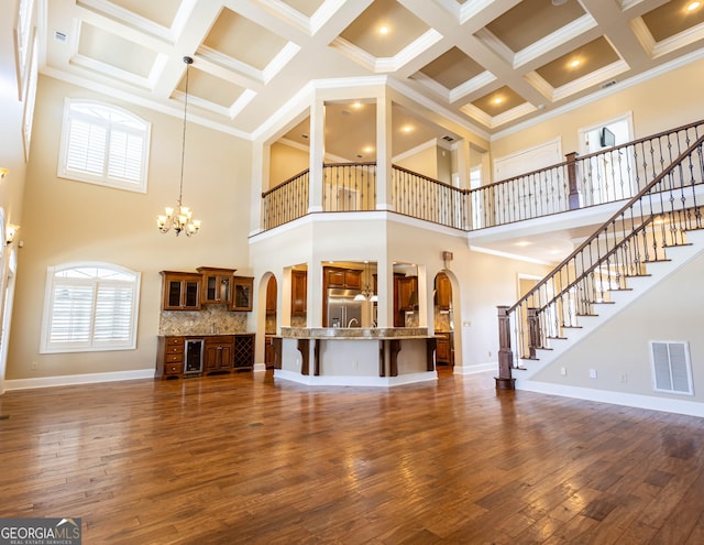 unfurnished living room featuring arched walkways, visible vents, a notable chandelier, and stairway