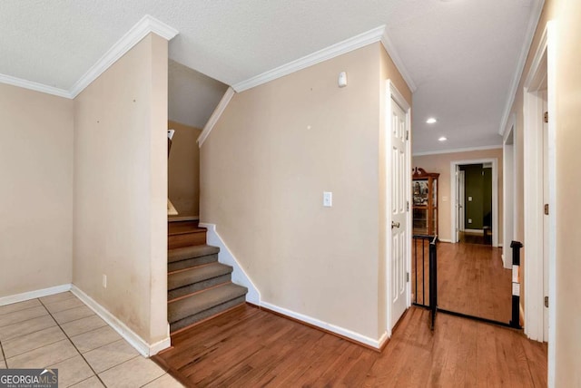 stairway with a textured ceiling, recessed lighting, wood finished floors, baseboards, and ornamental molding