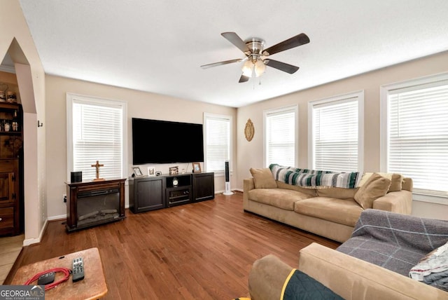 living room with baseboards, light wood-style flooring, and a ceiling fan