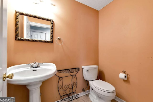 half bath featuring toilet, baseboards, and tile patterned floors