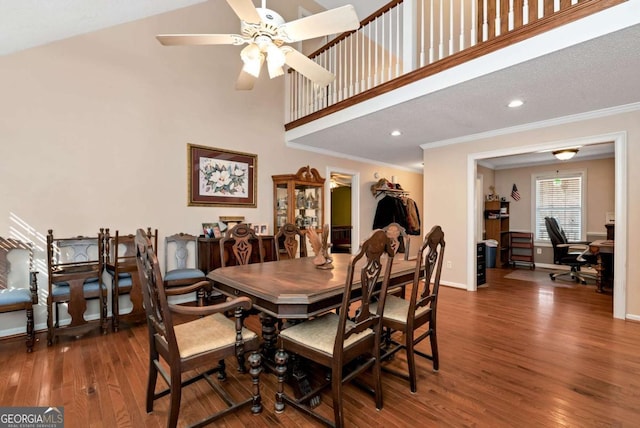 dining area featuring baseboards, ceiling fan, ornamental molding, wood finished floors, and a high ceiling