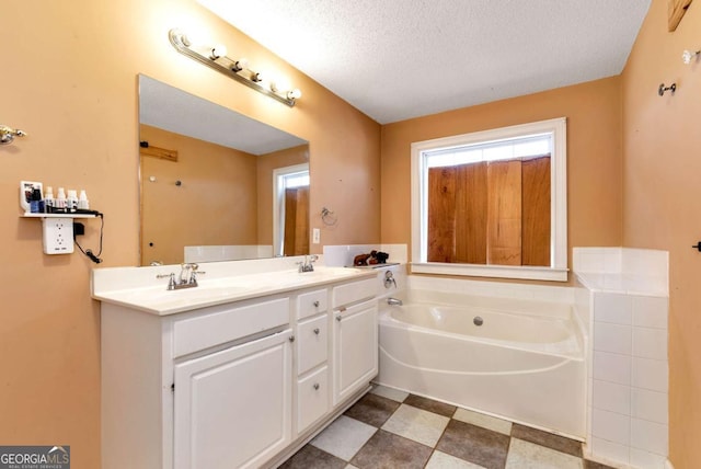 full bathroom with a garden tub, a textured ceiling, a sink, and tile patterned floors