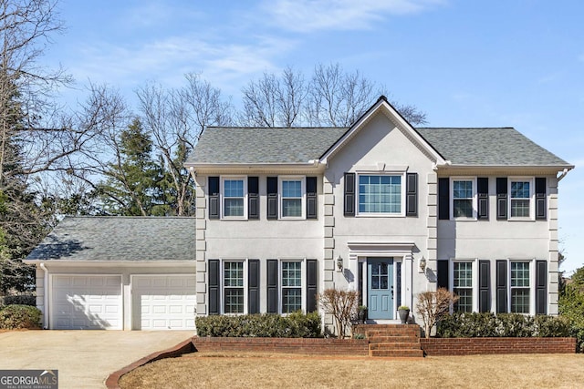 colonial house with an attached garage, concrete driveway, and stucco siding