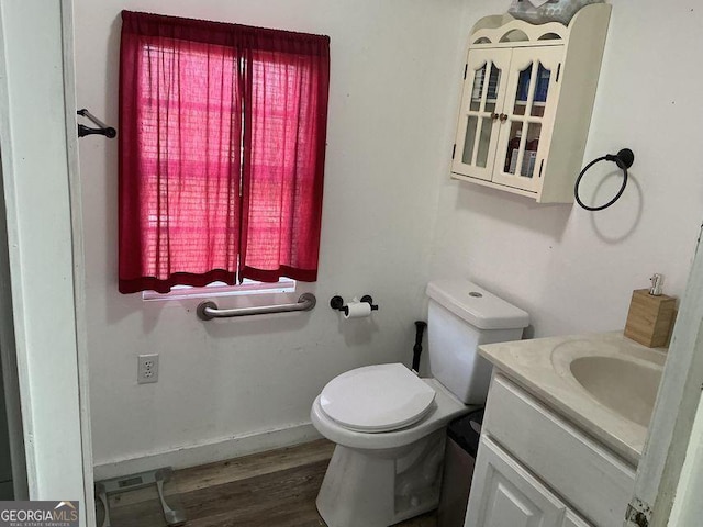 bathroom with toilet, wood finished floors, vanity, and baseboards