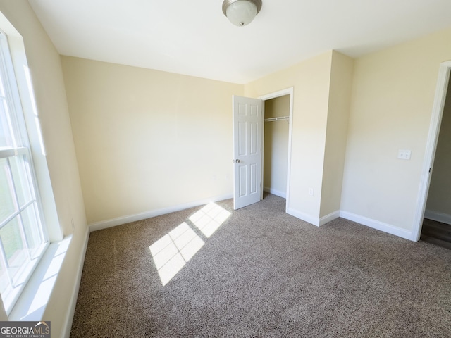 unfurnished bedroom featuring carpet floors, baseboards, and a closet