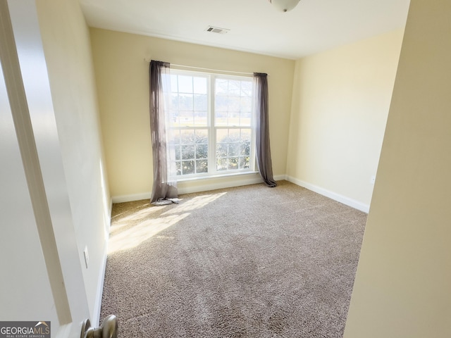 empty room with carpet floors, baseboards, and visible vents