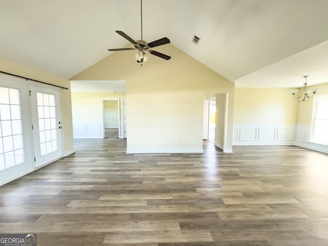 unfurnished living room featuring visible vents, a decorative wall, wood finished floors, and ceiling fan with notable chandelier