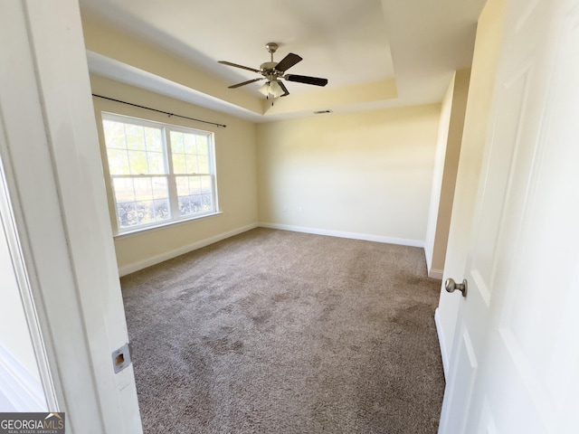 unfurnished room with visible vents, baseboards, a ceiling fan, carpet, and a tray ceiling