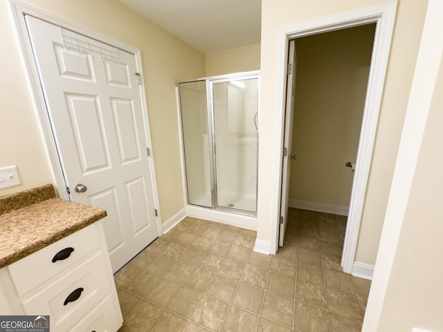 bathroom featuring a shower stall, baseboards, and vanity