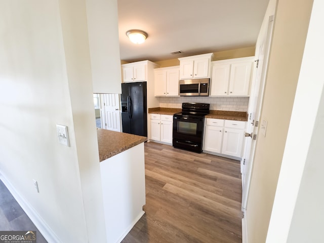 kitchen featuring dark countertops, white cabinetry, backsplash, and black appliances