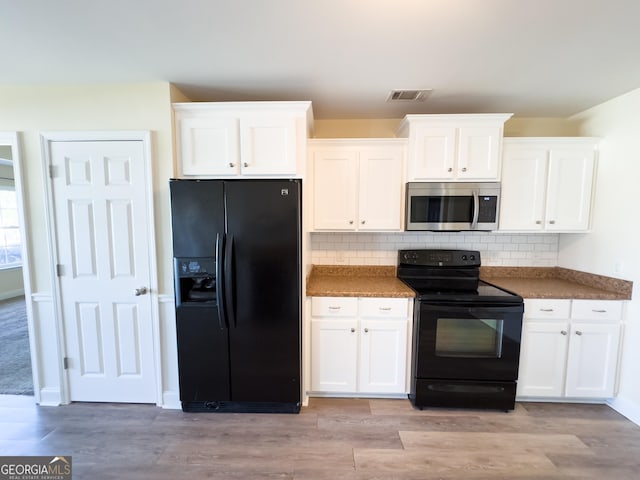 kitchen with visible vents, white cabinetry, light wood-type flooring, backsplash, and black appliances