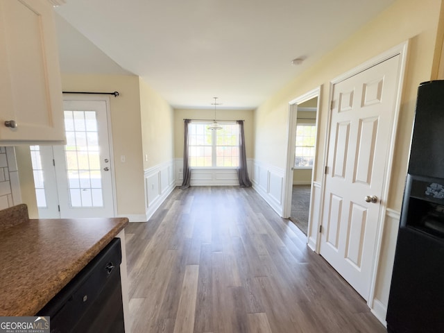 interior space with a wainscoted wall, a decorative wall, and dark wood-type flooring