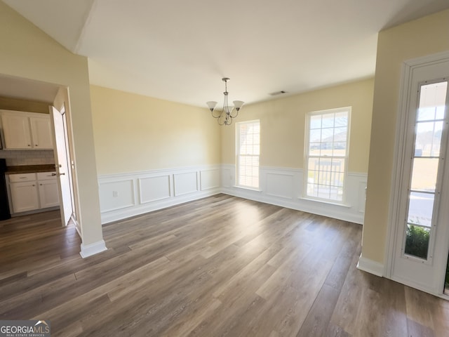 unfurnished dining area featuring wainscoting, dark wood finished floors, visible vents, and a notable chandelier