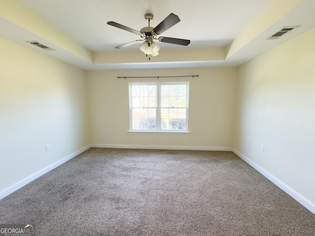 carpeted empty room featuring baseboards, visible vents, and a raised ceiling