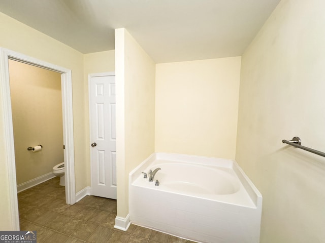 full bath featuring toilet, baseboards, and a bath