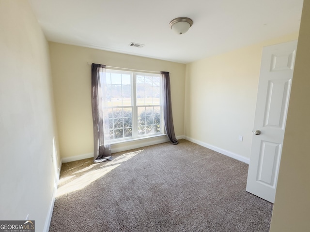 empty room with carpet, visible vents, and baseboards